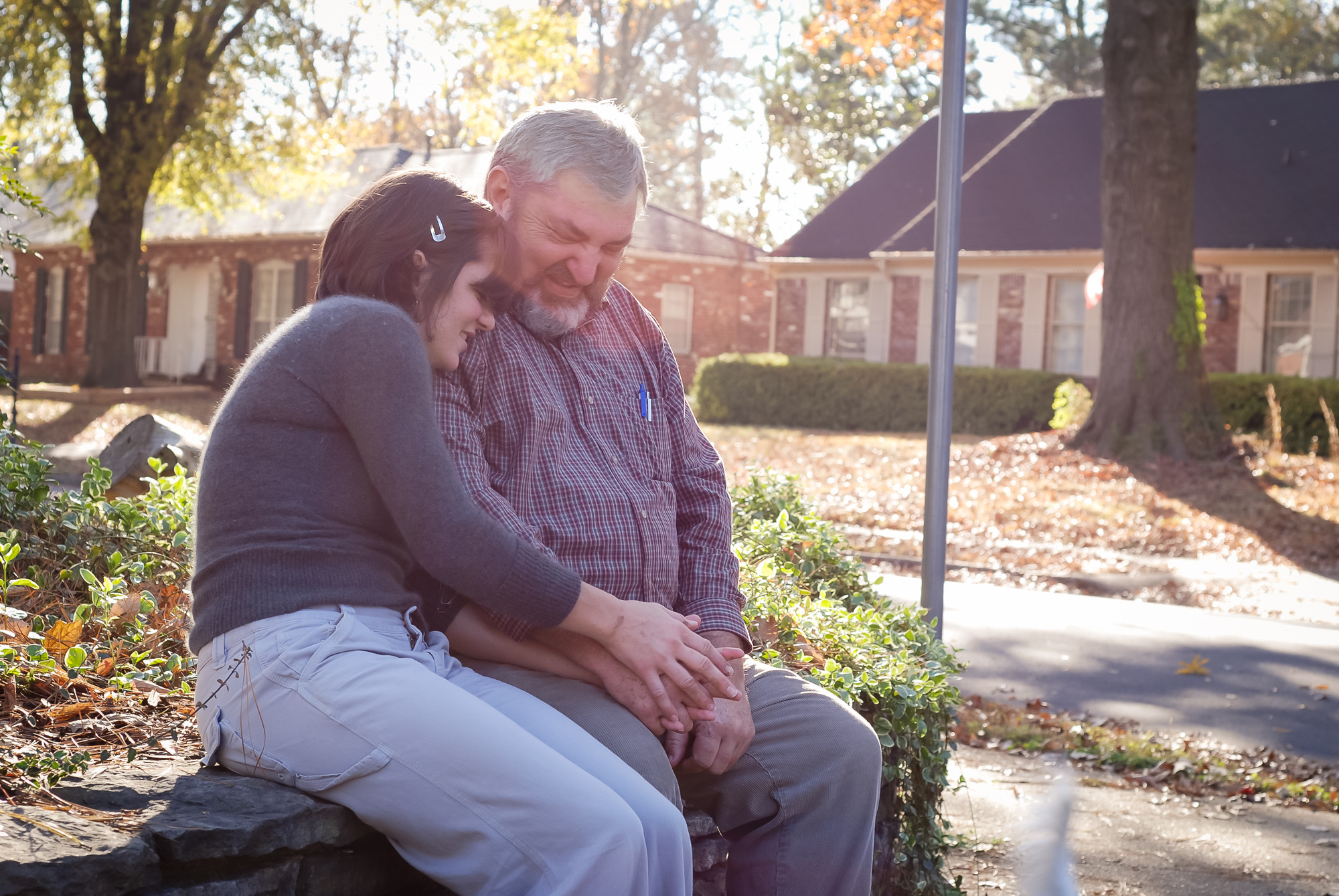 Danielle resting against her father's shoulder outdoors in the afternoon light